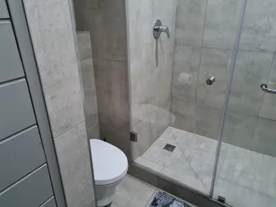 a bathroom with a toilet and a glass shower at Stunning City Living at Loftus in Pretoria