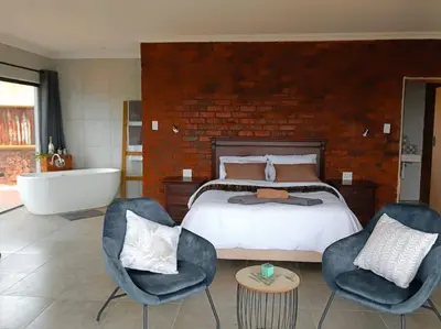 a bedroom with a bed and a tub and chairs at Rocky Road Mountain Lodge in Pretoria