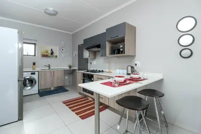 a kitchen with a white counter and stools in it at Smart Apartment 17 in Erand