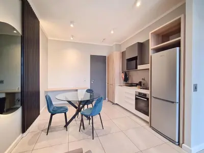 a kitchen with a table and blue chairs in a kitchen at 11 Floors in the Sky - Luxurious 1 Bedroom in Pretoria