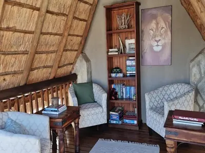 a living room with two chairs and a book shelf at The Dreamcatcher Lodge in Hoedspruit