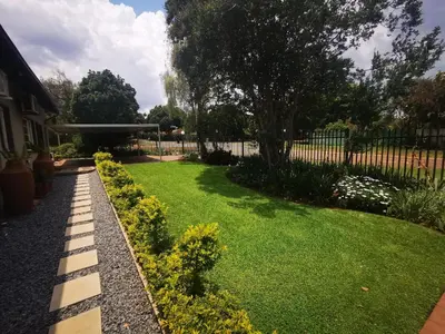 a garden with green grass and yellow flowers and a fence at Cozy Manor Guestrooms in Lyttelton
