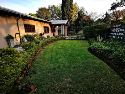 a yard with a house and a fence and grass at Cozy Manor Guestrooms in Lyttelton