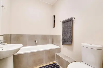 a bathroom with a tub and a toilet and a sink at The Lillies Luxury Apartment in Midrand
