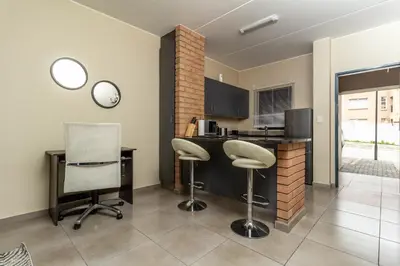 a kitchen with a desk and two chairs and a counter at The Lillies Luxury Apartment in Midrand