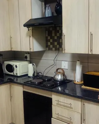 a kitchen with a stove and a microwave at KO'THABENG GUESTHOUSE in Lebowakgomo