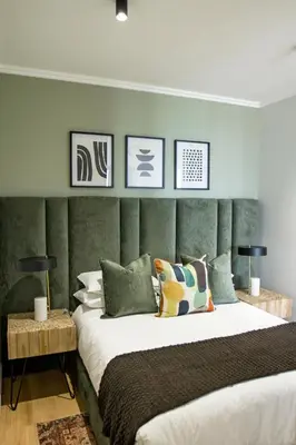 a bedroom with a large bed with a green headboard at Executive Apartment at Ellipse Waterfall in Midrand