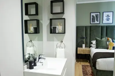a bedroom with a bed and a sink and a mirror at Executive Apartment at Ellipse Waterfall in Midrand