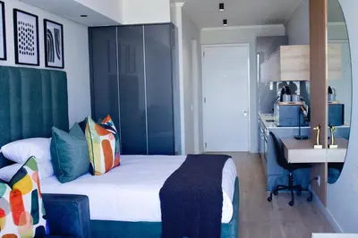a bedroom with a bed and a desk and a sink at Executive Apartment at Ellipse Waterfall in Midrand