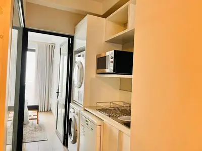 a kitchen with a microwave and a washer and dryer at The Regency Cozy Apartment- 629 in Pretoria