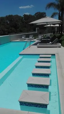 a large swimming pool with blue water and an umbrella at The Regency Cozy Apartment- 629 in Pretoria