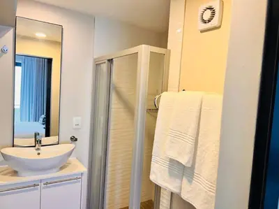 a white bathroom with a sink and a shower at The Regency Cozy Apartment- 629 in Pretoria