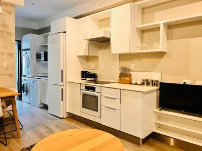 a kitchen with white cabinets and a tv in it at The Regency Cozy Apartment- 629 in Pretoria