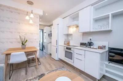 a kitchen with white cabinets and a wooden table at The Regency Cozy Apartment- 629 in Pretoria