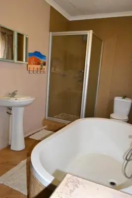 a bathroom with a tub and a toilet and a sink at On Golden Pond - Mount Amanzi in Hartbeespoort