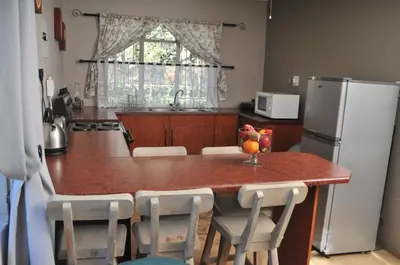 a kitchen with a table with chairs and a refrigerator at On Golden Pond - Mount Amanzi in Hartbeespoort