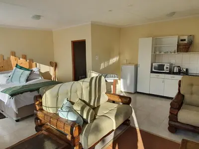 a bedroom with a bed and a couch and a chair at KatiKati Eco Lodge in White River