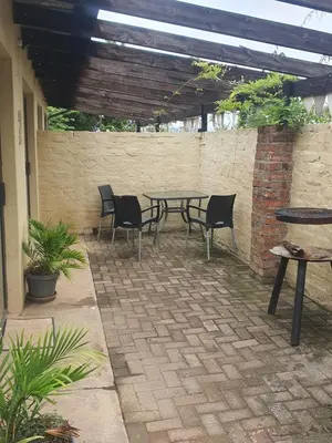 a patio with a table and chairs and a brick wall at KatiKati Eco Lodge in White River