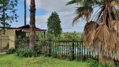 a fence in front of a house with a pool at KatiKati Eco Lodge in White River