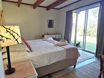 a bedroom with a bed and a large window at KatiKati Eco Lodge in White River