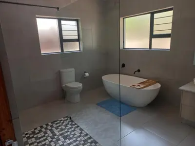a bathroom with a tub and a toilet andwindows at Make a memory in Marloth Park