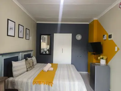 a bedroom with a bed with a yellow blanket at The Rose Guesthouse in Witbank