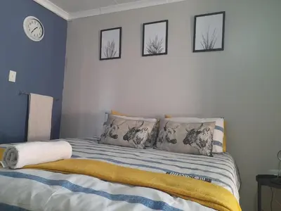 a bedroom with a bed with four pictures on the wall at The Rose Guesthouse in Witbank