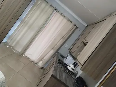 a small kitchen with a window and a curtain at The Rose Guesthouse in Witbank