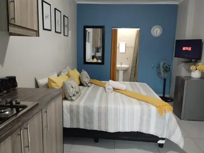 a room with a bed in a kitchen with blue walls at The Rose Guesthouse in Witbank