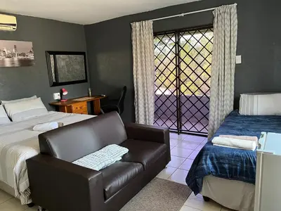 a bedroom with a couch and a bed and a window at Mlakalaka Guesthouse in KuMcogwaba