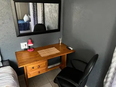 a desk in a bedroom with a mirror and a chair at Mlakalaka Guesthouse in KuMcogwaba