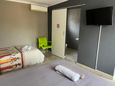 a bedroom with a bed and a flat screen tv at Mlakalaka Guesthouse in KuMcogwaba