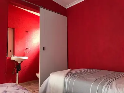a bedroom with red walls and a bed and a sink at Mlakalaka Guesthouse in KuMcogwaba