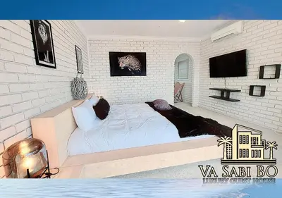 a white bedroom with a bed and a tv at Va sabi bo, Best View, Luxury Family Villa in Hartbeespoort Dam in Hartbeespoort