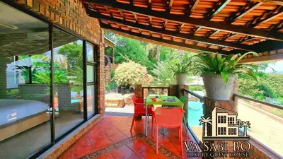 a patio with a table and chairs on a balcony at Va sabi bo, Best View, Luxury Family Villa in Hartbeespoort Dam in Hartbeespoort