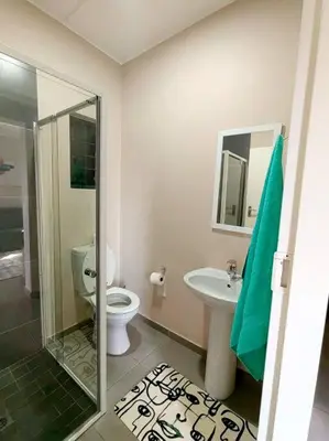 a bathroom with a shower and a toilet and a sink at Modern 2 bedroom at Waterfall Ridge-Midrand in Midrand