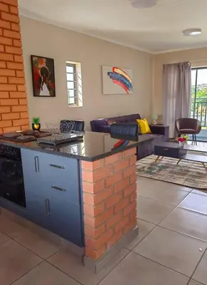 a kitchen with an island in a living room at Modern 2 bedroom at Waterfall Ridge-Midrand in Midrand