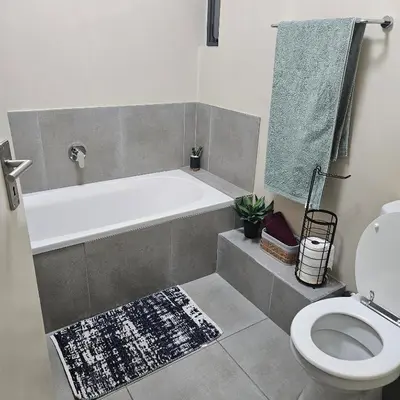 a bathroom with a bath tub and a toilet at Modern 2 bedroom at Waterfall Ridge-Midrand in Midrand