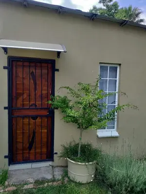 a house with a wooden door and a tree in a pot at Outside room in Pretoria