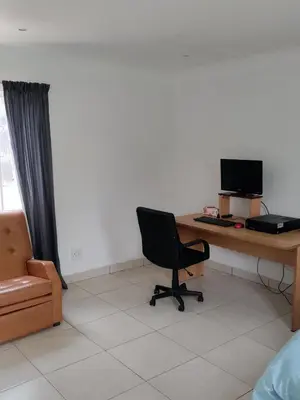 a room with a desk with a computer and a chair at Outside room in Pretoria