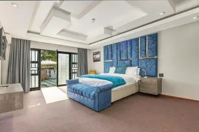 a bedroom with a bed and a blue wall at Summit Della Suite in Centurion