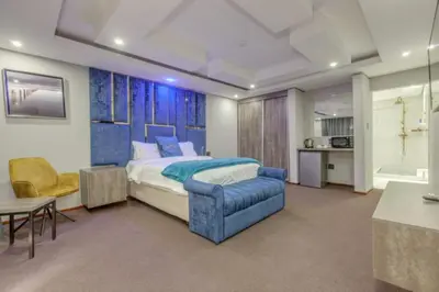 a bedroom with a king sized bed and a blue chair at Summit Della Suite in Centurion