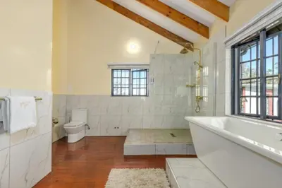 a white bathroom with a tub and a toilet at Summit Della Suite in Centurion