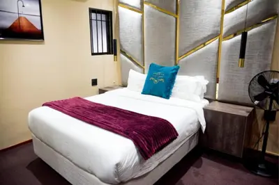 a bedroom with a large bed with a blue pillow on it at Summit Della Suite in Centurion