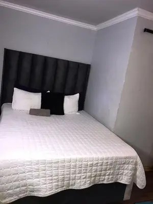 a bedroom with a white bed with a black headboard at Black Owl Lodge in Kempton Park