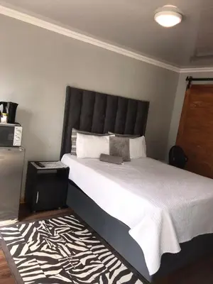 a bedroom with a large bed with a black headboard at Black Owl Lodge in Kempton Park
