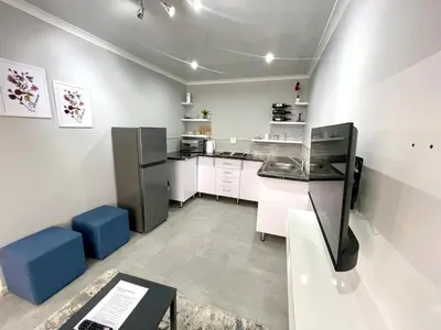 a kitchen with white cabinets and blue stools at Reros Apartments in Mankweng in Mankweng