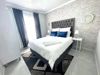 a bedroom with a large bed with blue pillows at Reros Apartments in Mankweng in Mankweng