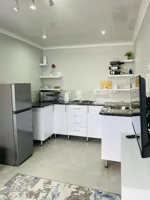 a large white kitchen with white cabinets and appliances at Reros Apartments in Mankweng in Mankweng