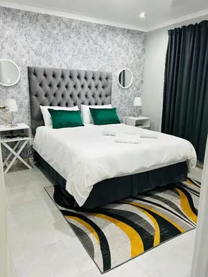 a bedroom with a large bed with green pillows at Reros Apartments in Mankweng in Mankweng
